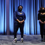 people stand on stage wearing face masks