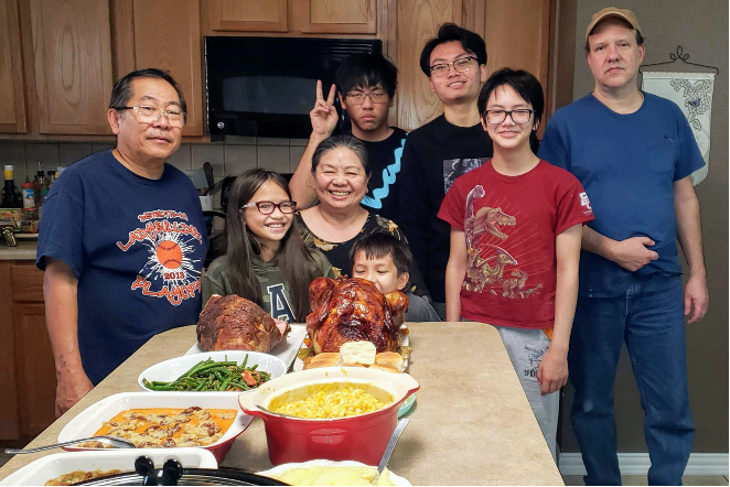 group of people pose together around dinner table with food in house