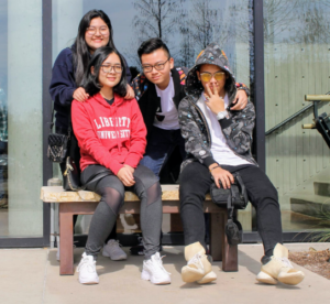 four people sit on bench near glass building during daytime