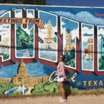 woman stands in front of "Austin" mural during daytime