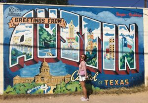 woman stands in front of "Austin" mural during daytime