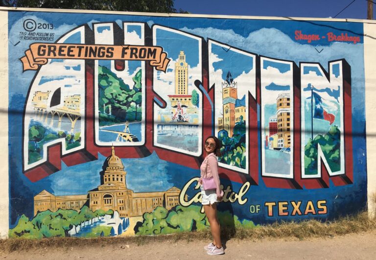 woman stands in front of "Austin" mural during daytime