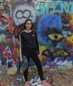 woman stands in front of graffitied wall
