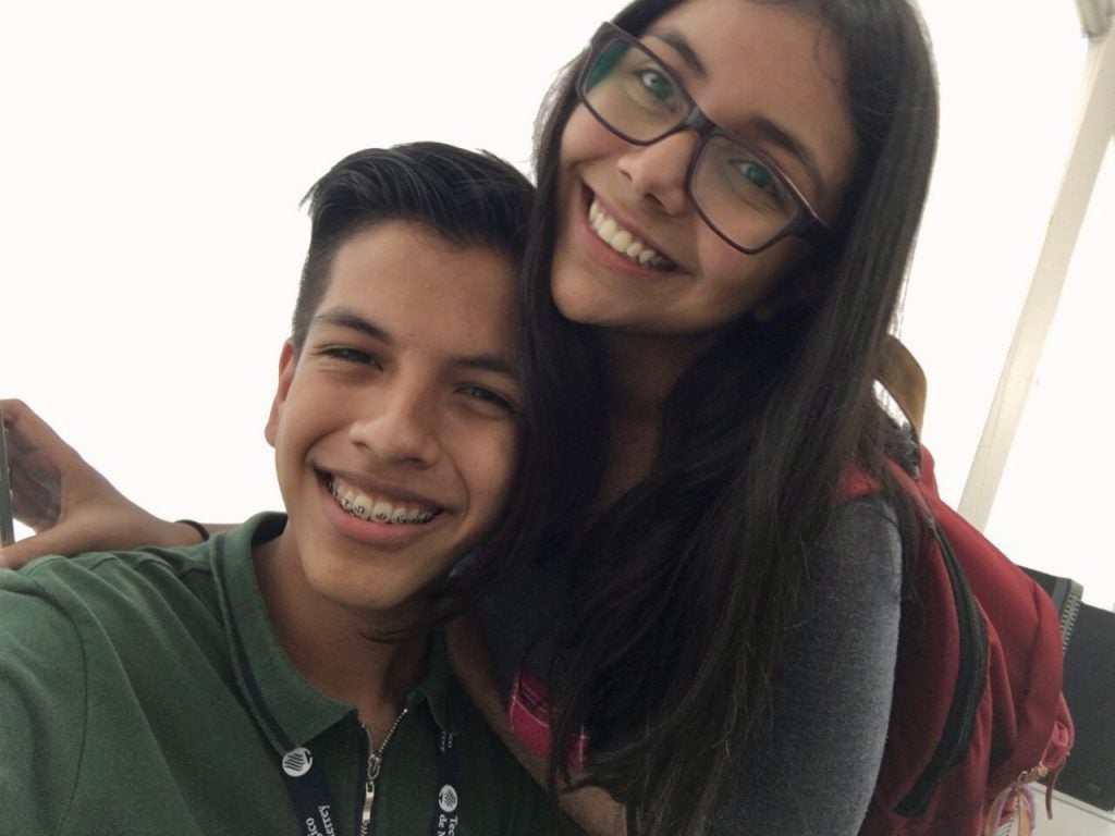 Abrego with friend wearing red backpack smiling and taking a selfie