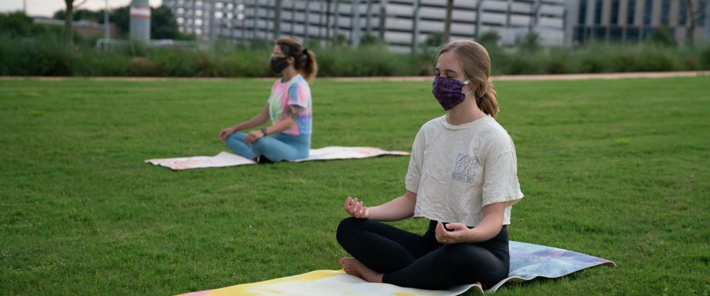 students doing yoga and wearing masks on the grass