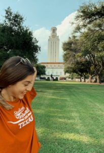 Cagla smiles in front of the UT tower and lawn on a summer day.