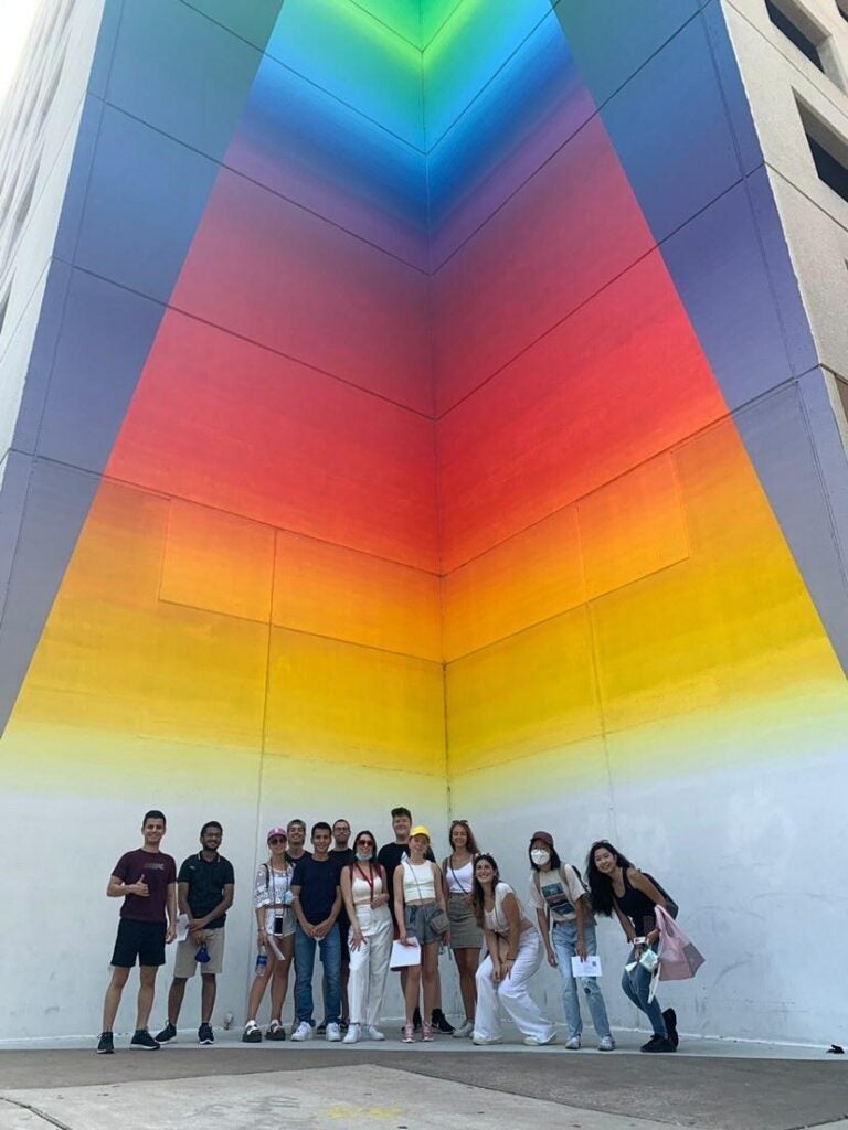 students pose in front of a colorful art installation backdrop