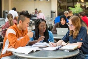 Three students gather outside of the Union, studying together. 