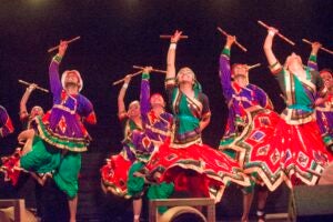 Dance crew performs traditional Indian dance on stage. 