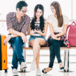 Three students wait in the airport with their baggage