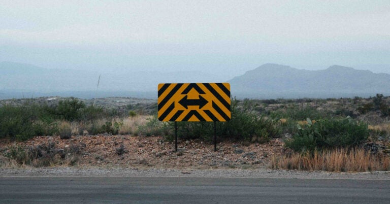 A two-way road sign looking over a cliff