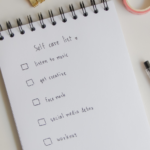 Self care list on notebook with office supplies
