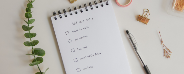 Self care list on notebook with office supplies