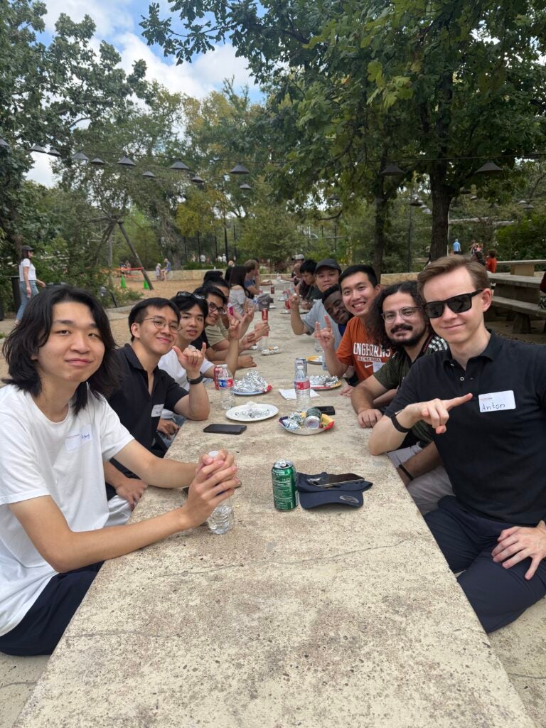 Diverse student group sitting together along a long table at a park