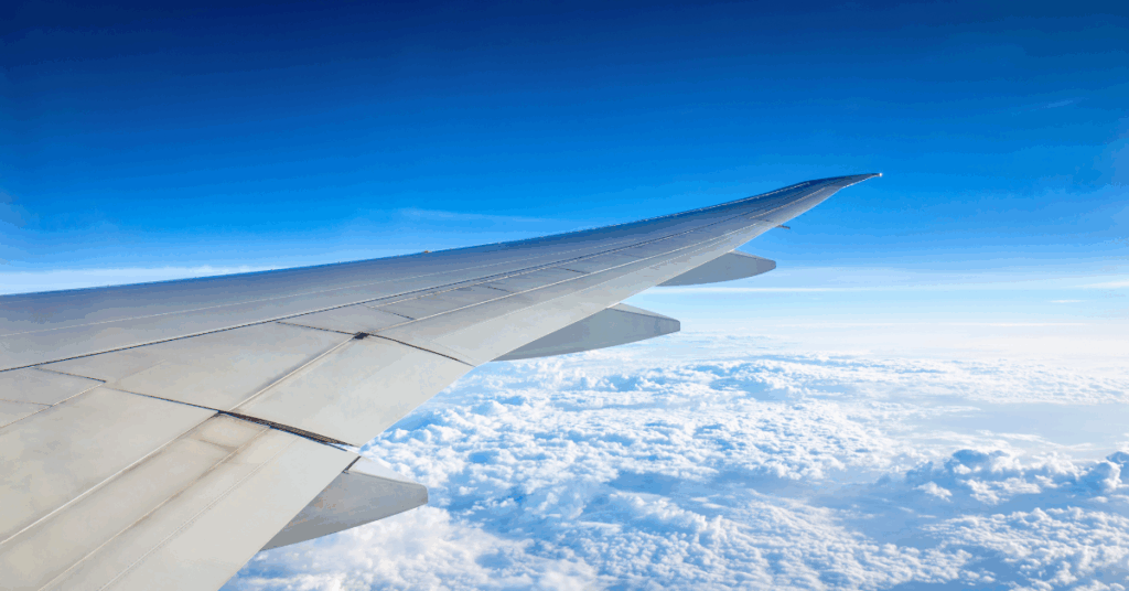 View of looking out to a plane wing soaring above the clouds