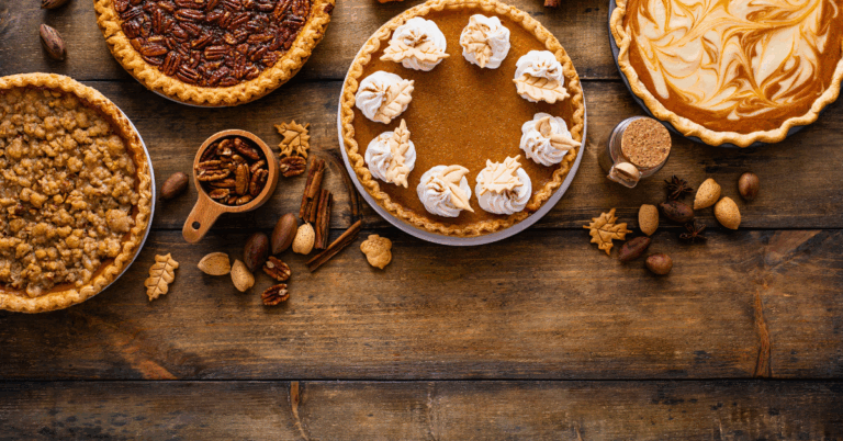 An assortment of different types of pies often enjoyed at Thanskgiving meals are displayed on a aged wooden table