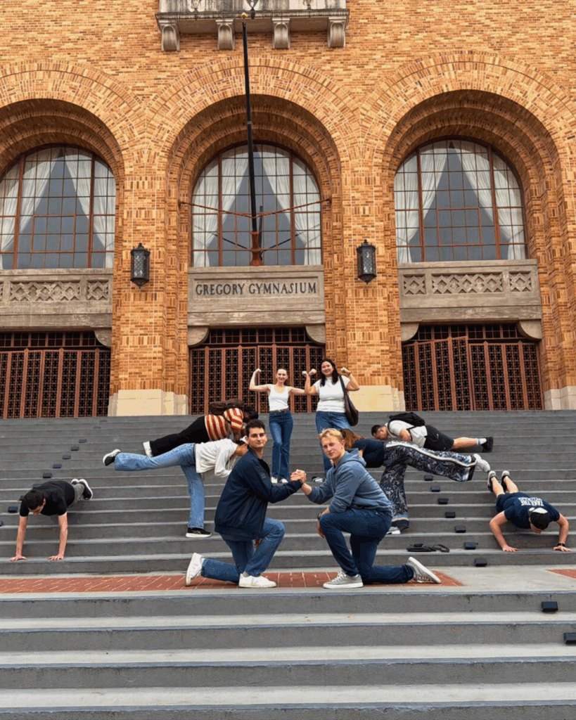 Students sitting together along the steps in front of Greg Gym
