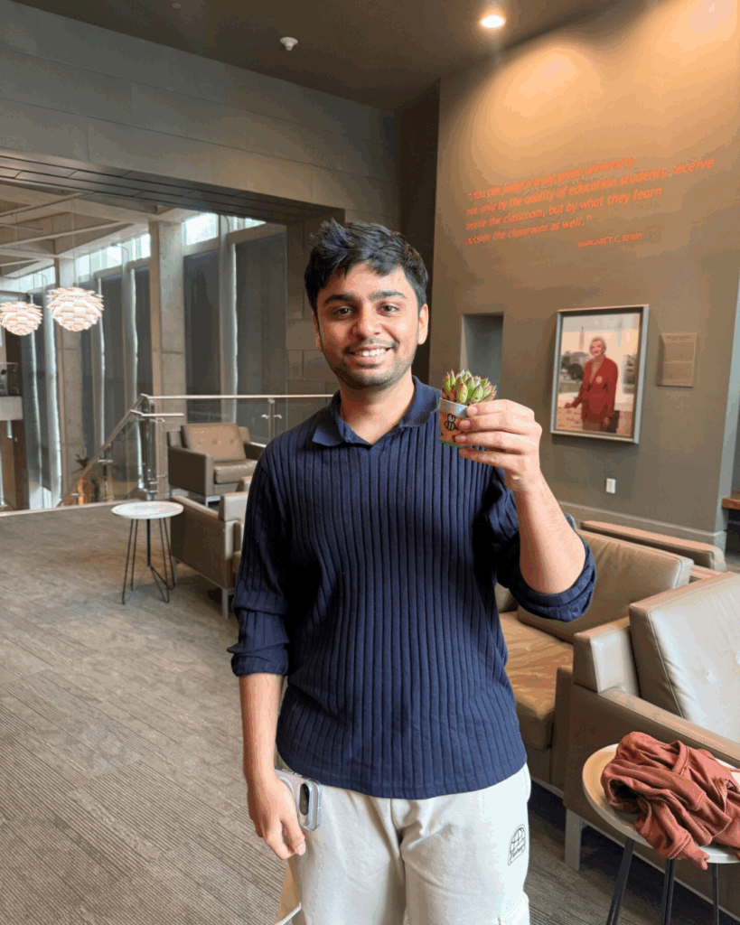 Student holding their small plant and small pot with their design on it