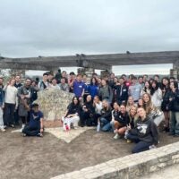 Large student group taking picture together at the top of Mount Bonnell in Austin, TX