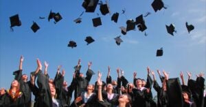 Graduating students in their gowns toss their caps in the air