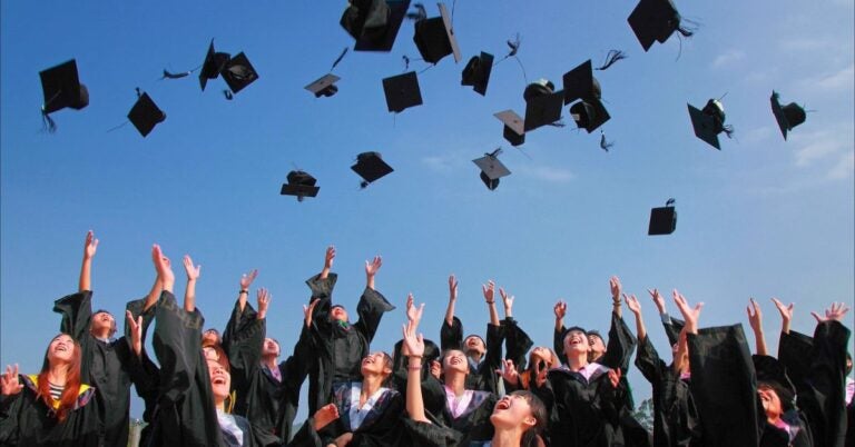 Graduating students in their gowns toss their caps in the air