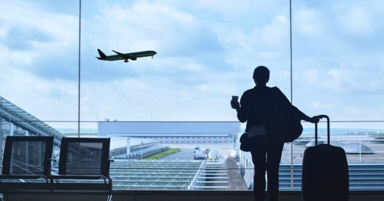Person at airport watching airplane takeoff