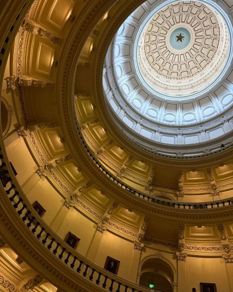 View of an ornate, spiraling dome ceiling with a central star design. Warm lighting highlights intricate architectural details, creating an elegant ambiance.