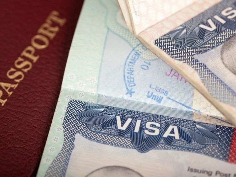 A close-up view of a United States passport partially overlapping a visa within another passport.