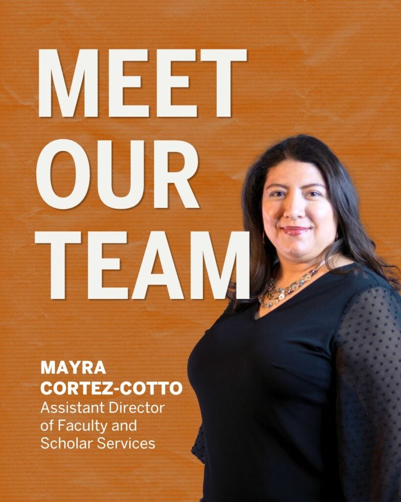 Portrait of a smiling woman in black against an orange background. Text reads "Meet Our Team. Mayra Cortez-Cotto, Assistant Director of Faculty and Scholar Services."