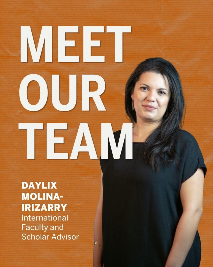 a woman standing against a textured, orange background. She is positioned on the right side of the image, wearing a simple black blouse. Her dark hair falls to one side, and she has a subtle, confident smile. On the left side of the image, bold white text reads "MEET OUR TEAM" and below that, in slightly smaller text, her name and title are displayed.